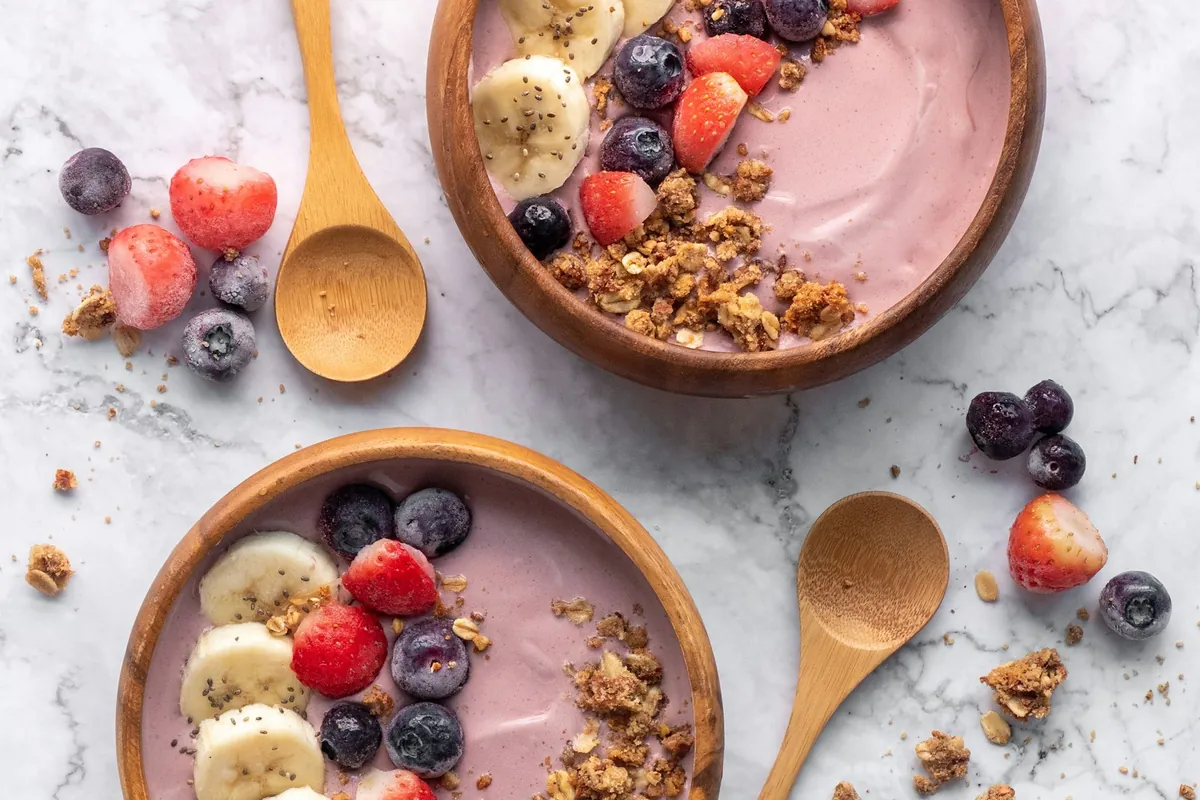Duas tigelas de açaí com banana, frutas e granola para compartilhar